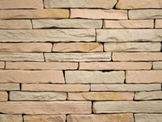Voľne kladený fasádny obklad s prirodzenou štruktúrou v pieskovej farbe.